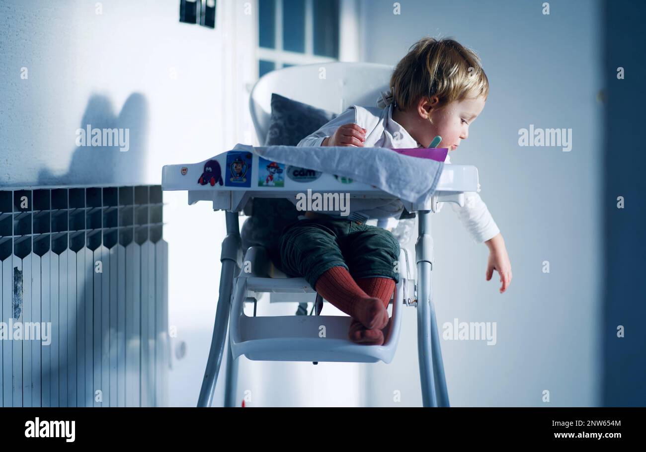 Ein kleiner Junge im Hochstuhl, der zur Seite greift Stockfoto