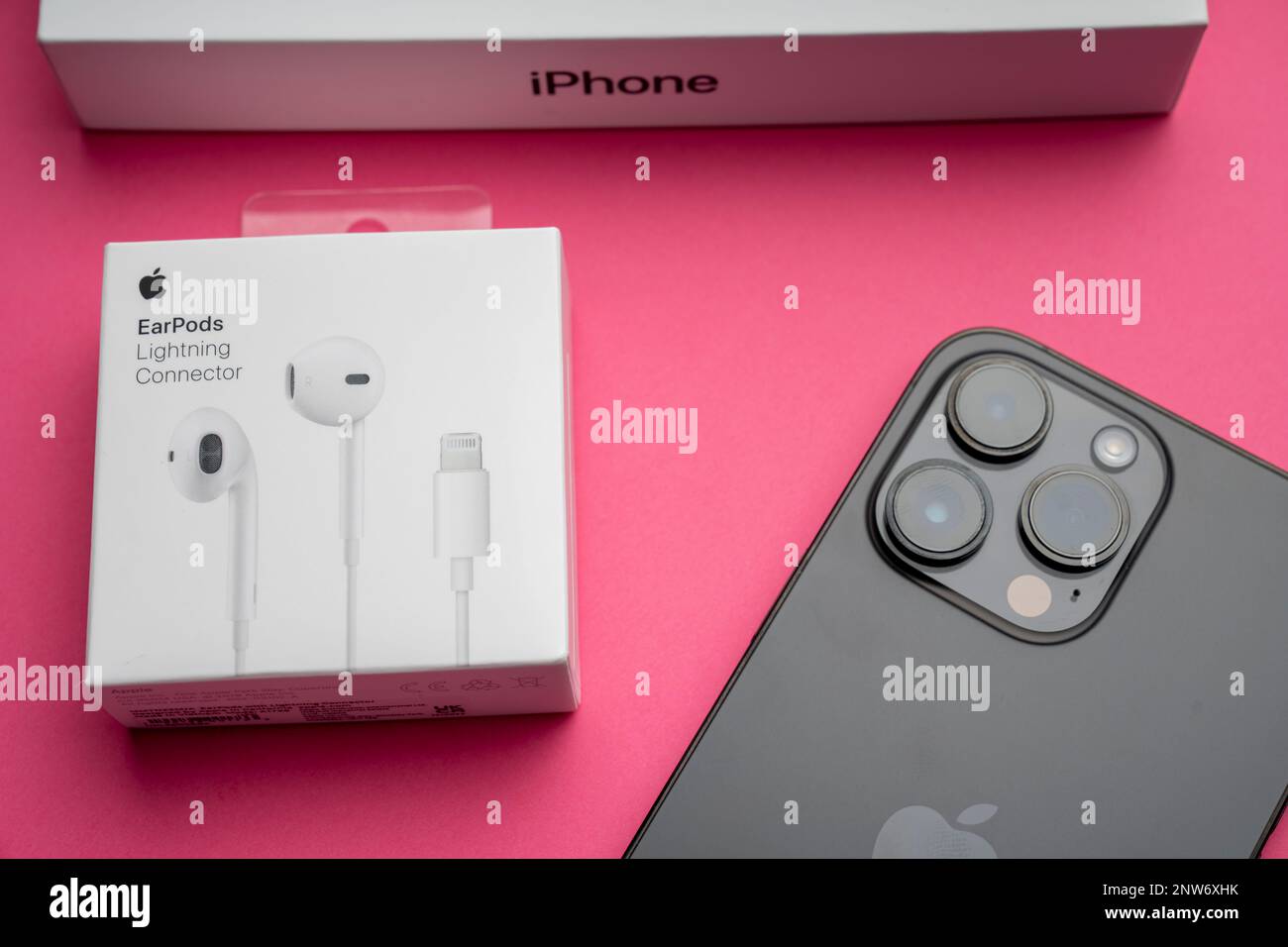 Neue iPhone 14 pro max und Apple Ohrhörer, AirPods weiße Ohrhörer zum Anhören von Musik und Podcasts in einer geschlossenen Box. Isolierter rosafarbener Hintergrund. Budap Stockfoto
