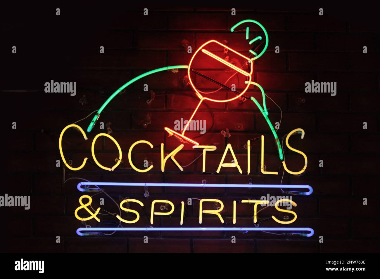 Ein Neonlicht, das in den Ausdruck „Cocktails & Spirituosen“ mit einem Cocktailglas darüber geformt ist. Stockfoto