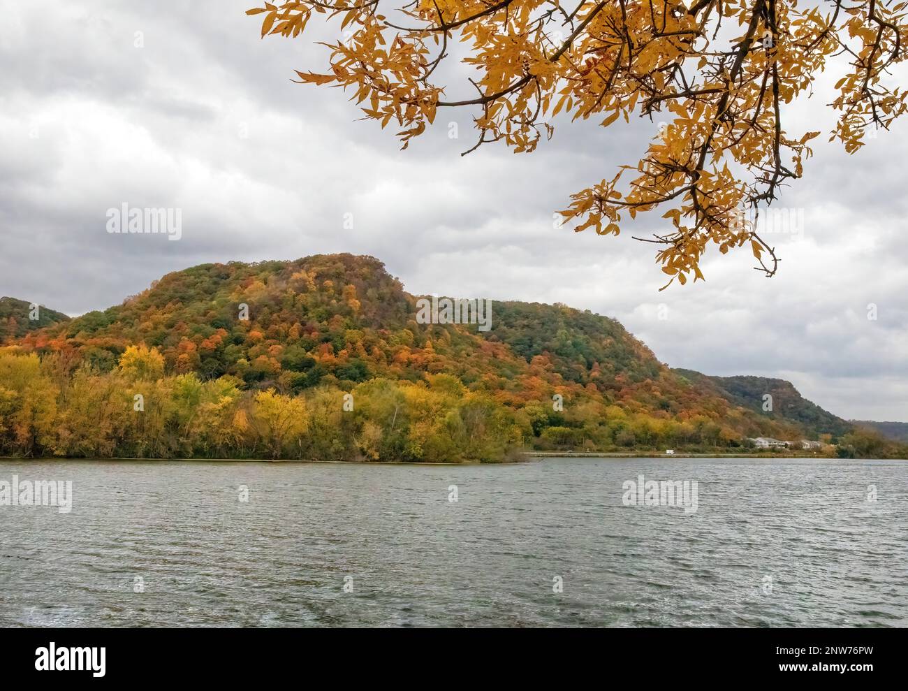 West Lake Winona mit seinen Klippen und Bäumen, die an einem wolkigen Herbsttag in Winona, Minnesota, USA, ihre Herbstfarben zeigen. Stockfoto