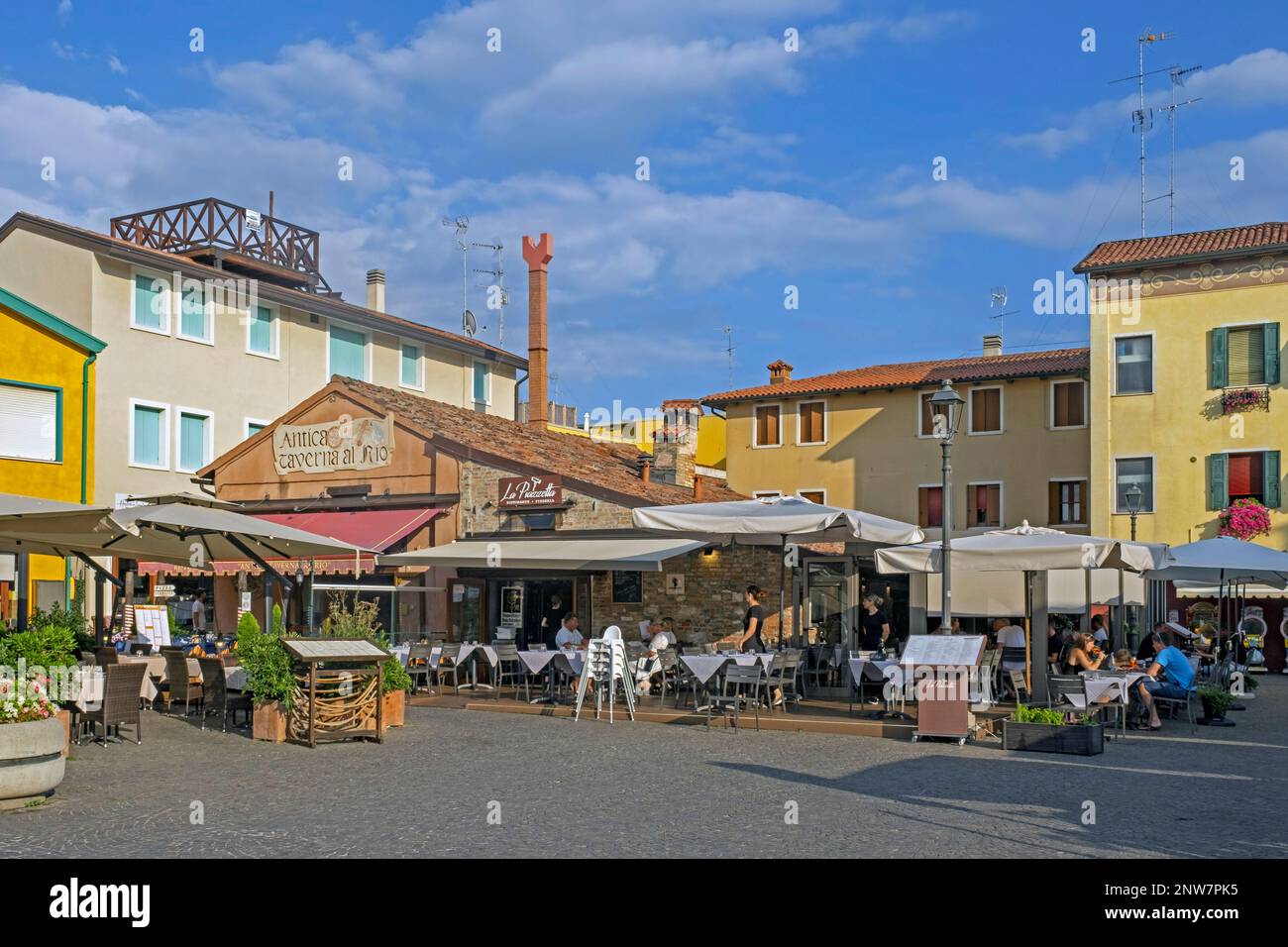 Touristen besuchen Restaurants im historischen Stadtzentrum von Caorle, der Küstenstadt der Metropolstadt Venedig, Veneto, Norditalien Stockfoto