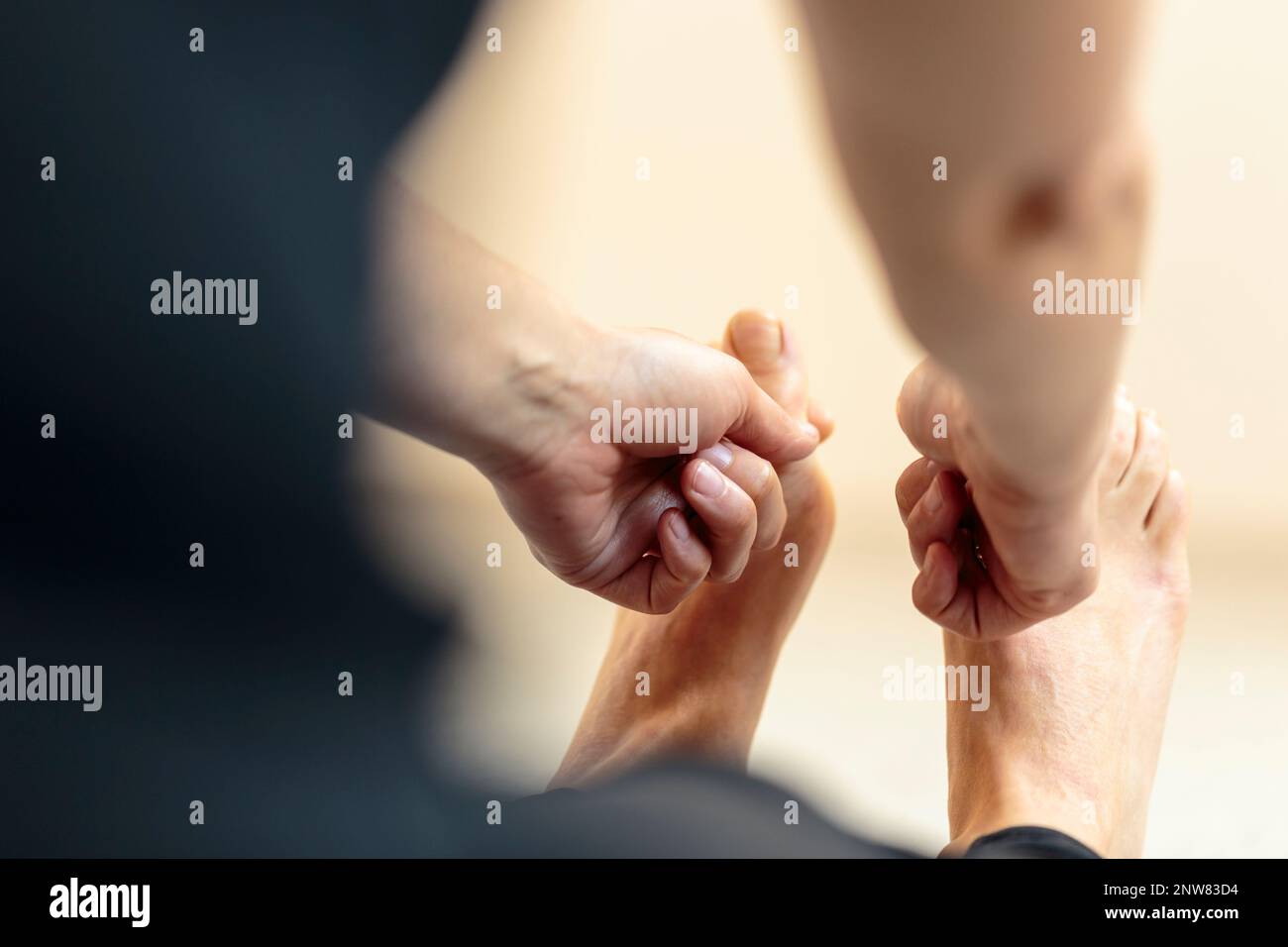 Yoginis, die sich auf dem Boden nach vorn beugen, den Fuß strecken und Zeigefinger und Daumen mit beiden Händen an den Yoga-Zehen halten Stockfoto