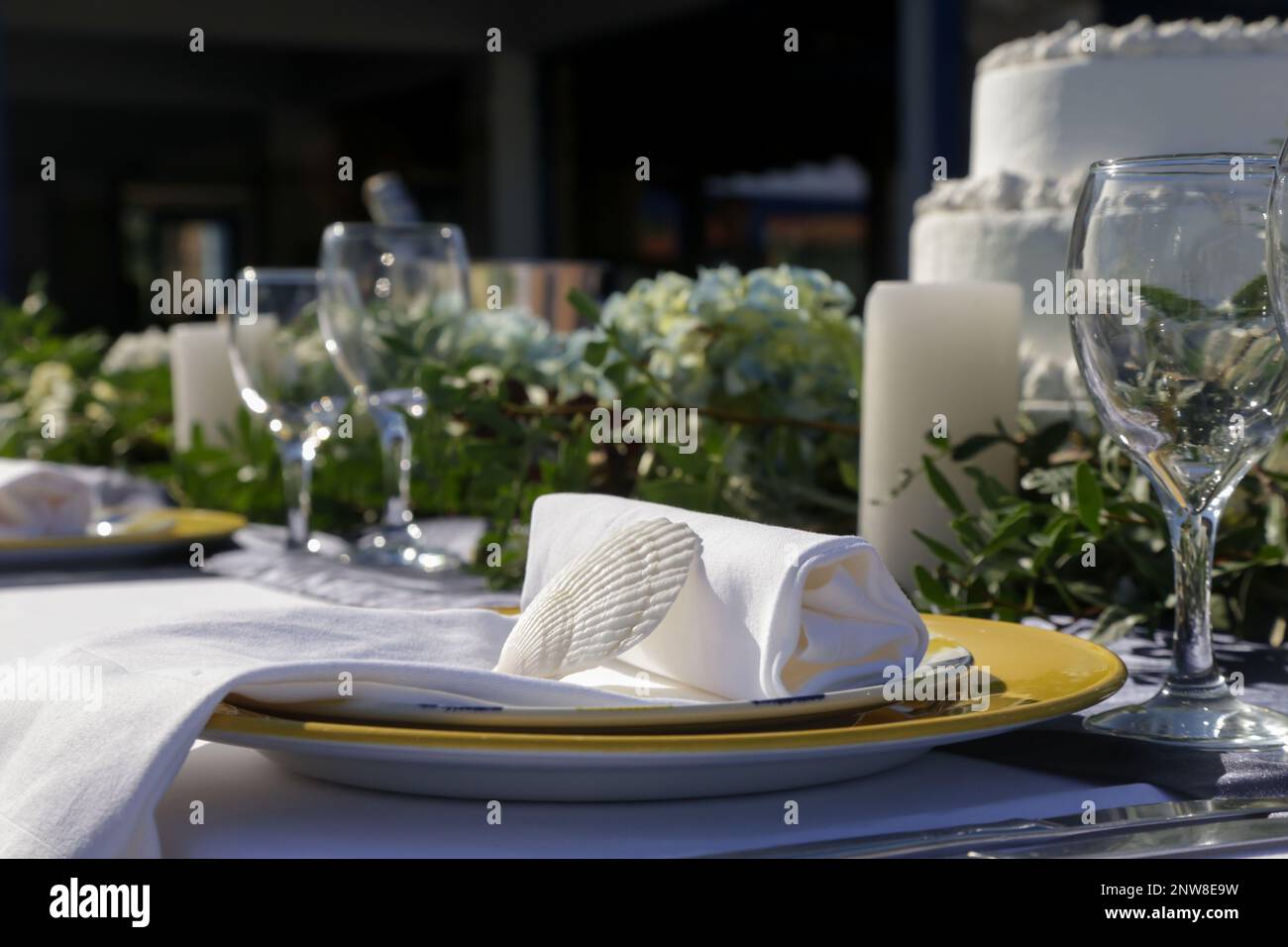 Elegante Tischgestaltung mit grünem Busho-inspiriertem Herzstück, Muscheln und weißem Leinentuch für eine Verlobungsfeier, einen Hochzeitsempfang oder Stockfoto