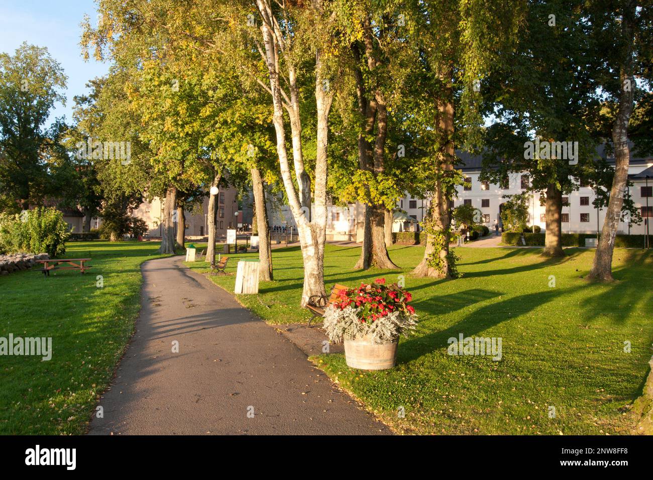 Promenade und Park in der Nähe der Abtei Vadstena, Schweden. Blick vom Pfad, Blumen und Bäume. Stockfoto