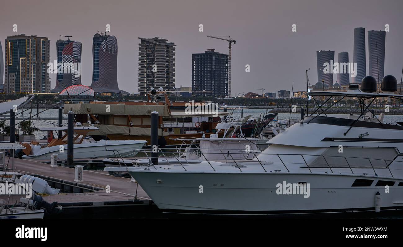 Lusail Marina in Lusail City, Katar Sonnenuntergang Aussicht mit Yachten und Booten mit Katar Flagge, Lusail Skyline und Wolken am Himmel im Hintergrund Stockfoto