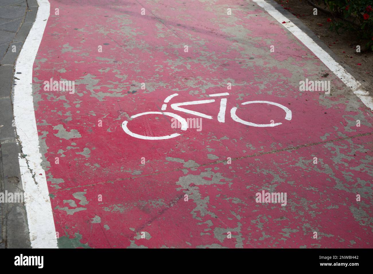 Rote Fahrspur und Farbe, die von der Zeit getragen wurden, in der das Symbol eines Fahrrads auf dem Asphalt gemalt wurde, was darauf hinweist, dass zweirädrige Fahrzeuge wie z. B. Fahrräder Stockfoto