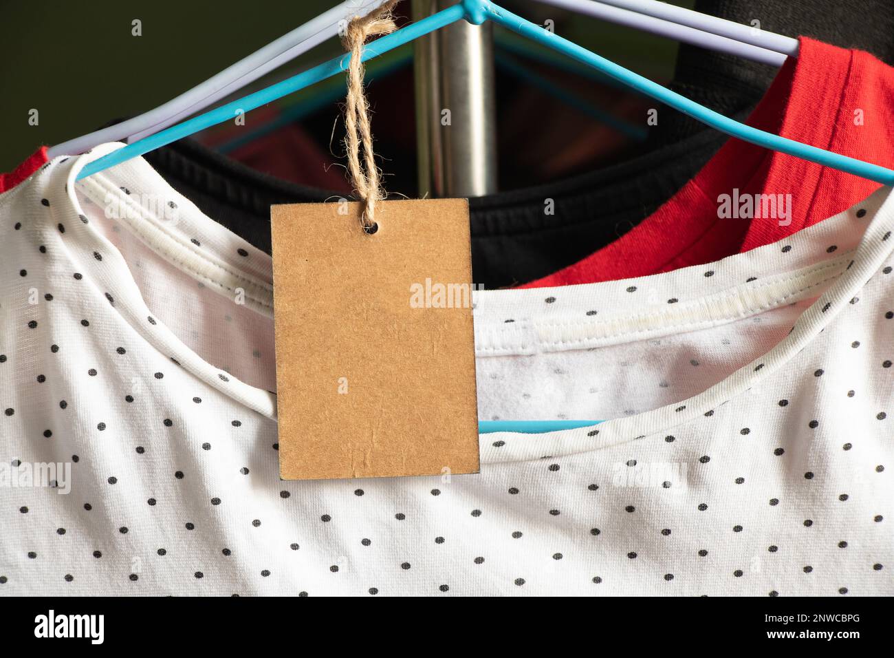Karton, Verpackung, lässig, Kleidung, Branding, Shopping, braunes Papier Preisschild wiegt auf Kleidung auf einem Rack auf einem Kleiderbügel im Verkaufsbereich, blank pri Stockfoto