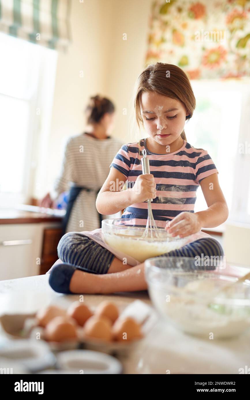 Shes a whiz with a wisk. Aufnahme eines kleinen Mädchens, das ihrer Mutter beim Backen in der Küche half. Stockfoto