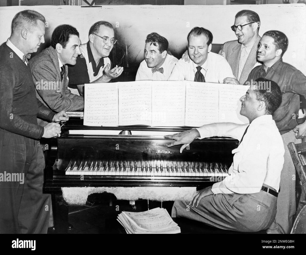 Benny Goodman (Dritter von links) mit einigen seiner ehemaligen Musiker, die von links nach rechts um das Klavier sitzen: Vernon Brown, George Auld, Gene Krupa, Clint Neagley, Ziggy Elman, Israel Crosby und Teddy Wilson (am Klavier). Benjamin David Goodman (1909 – 1986), amerikanischer Klarinetist und Bandleader, bekannt als „König des Swing“. Stockfoto