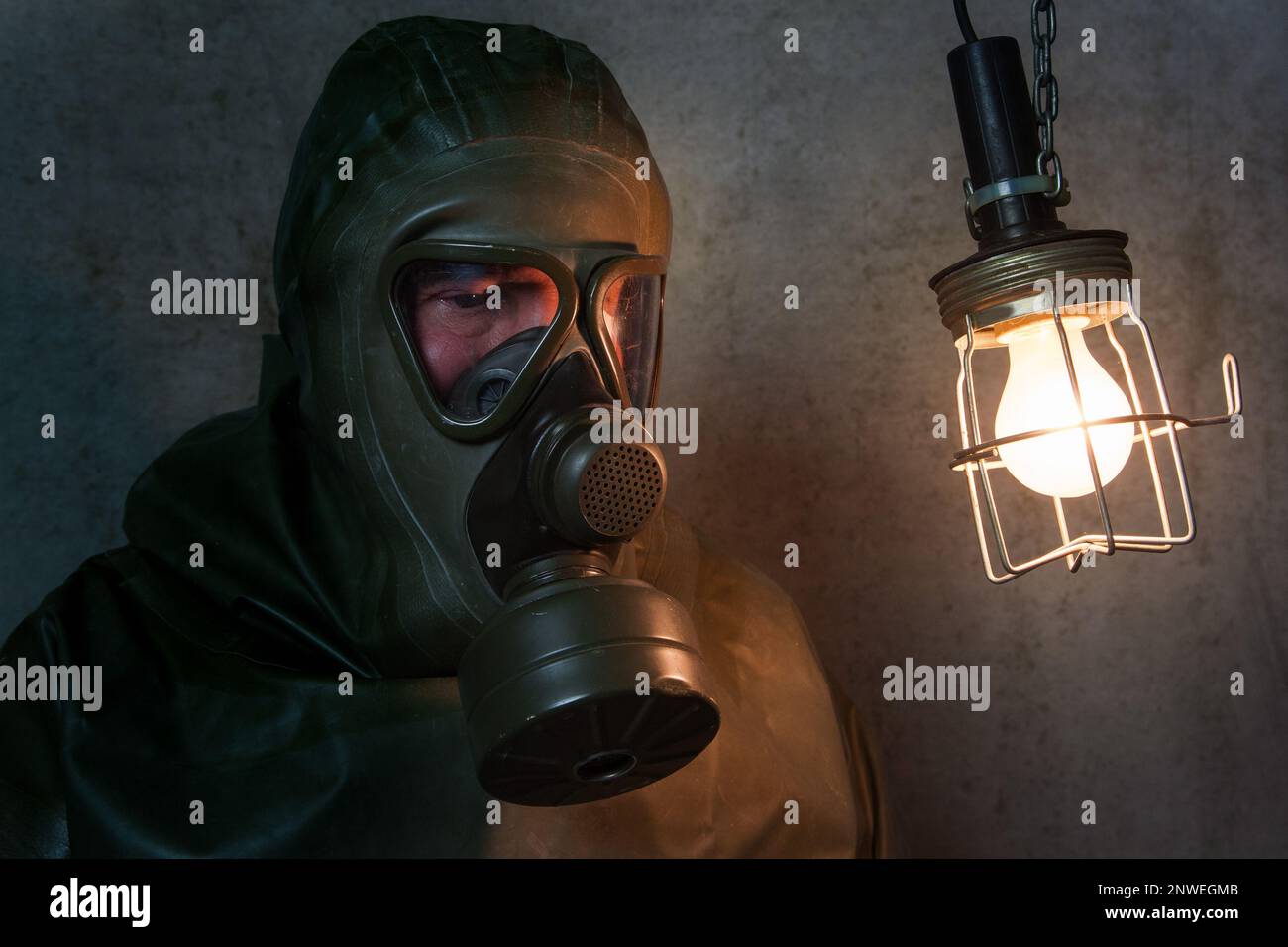 Ein Mann in seinem NBC-Schutzanzug sitzt in seinem Keller und hat Angst vor einem Atomkrieg. Die Drohung des Kremls mit Atomwaffen funktioniert. Stockfoto