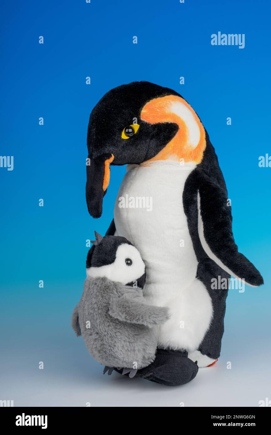 Ausgestopfte Tiere mit Kaiserpinguin für Erwachsene und Babys auf einem nahtlosen blau-weißen Hintergrund. Stockfoto