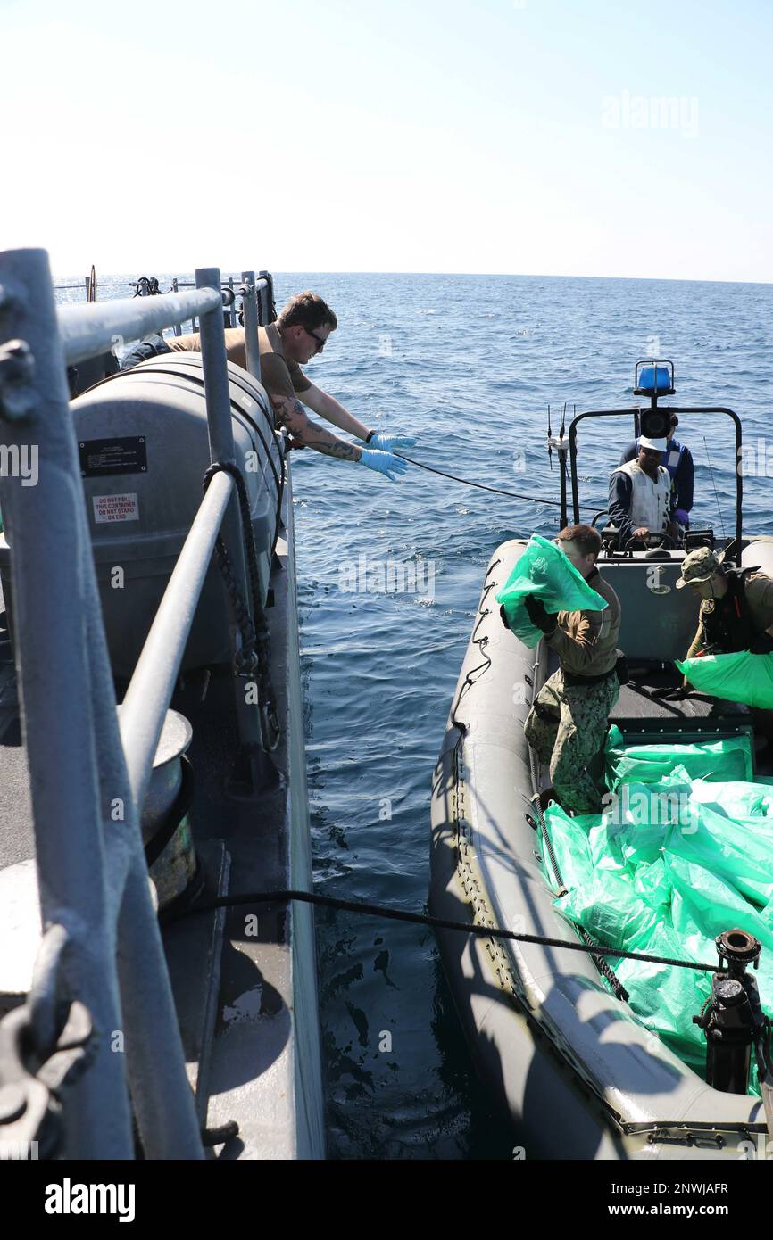 230106-N-NO146-1002 GOLF VON OMAN (6. Januar 2023) Seeleute des Küstenschiffes USS Chinook (PC 9) transferieren Waffen, die von einem Fischereifahrzeug in den internationalen Gewässern des Golfs von Oman beschlagnahmt wurden, Januar 6. Die US-Marinestreitkräfte beschlagnahmten 2.116 AK-47-Sturmgewehre von einem Fischereifahrzeug, das auf einer Seeverkehrsroute vom Iran nach Jemen unterwegs war. Stockfoto
