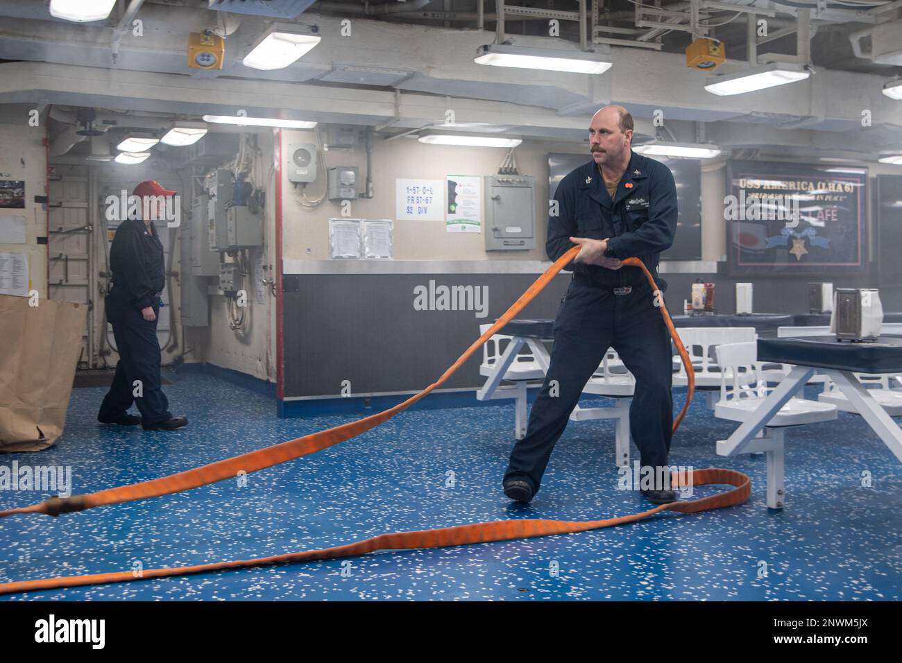 PHILIPPINE SEA (28. Januar 2023) Hull Maintenance Technician 1. Class Christopher Cherrix, aus Copperas Cove, Texas, dem nach vorn eingesetzten Amphibienflugzeugträger USS America (LHA 6) zugewiesen, rollt während einer Übung zur Schadensbegrenzung auf den Schiffsdecks einen Feuerwehrschlauch aus, während er in der Philippinischen See segelt; Januar 28. America, das führende Schiff der America Amphibious Ready Group, ist im 7.-Flottenbereich tätig. 7. Fleet sind die USA Die größte Flotte der Navy, die mit einer Anzahl von Flotten ausgestattet ist, arbeitet regelmäßig mit Alliierten und Partnern zusammen, um eine freie und offene Flotte zu erhalten Stockfoto