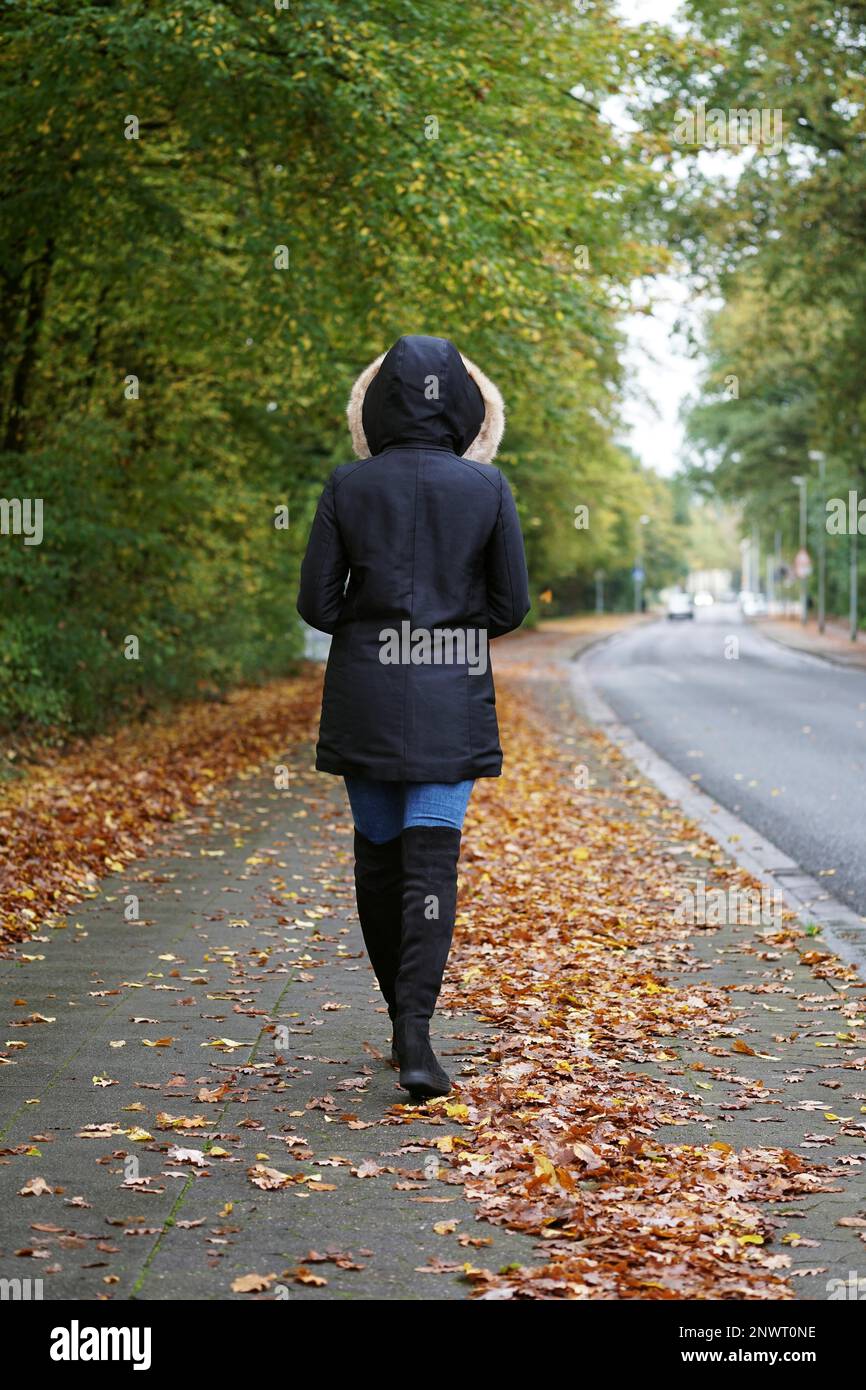 Ansicht der Rückseite des unkenntlich Frau Winter Mantel und Stiefel zu Fuß die Straße im Herbst Stockfoto