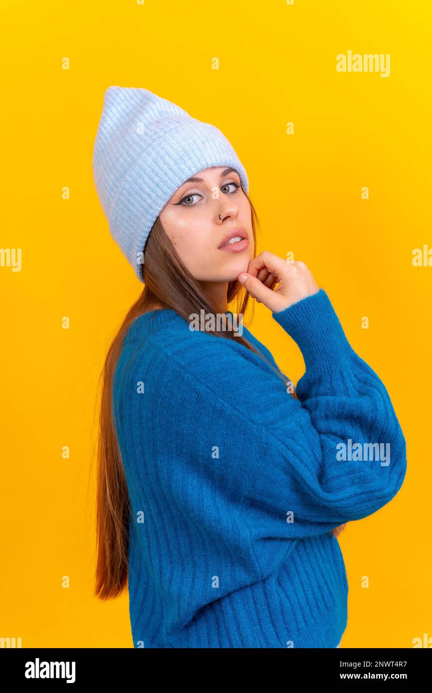 Nahaufnahme einer jungen Kaukasierin in blauem Wollpullover isoliert auf gelbem Hintergrund im Studio Stockfoto