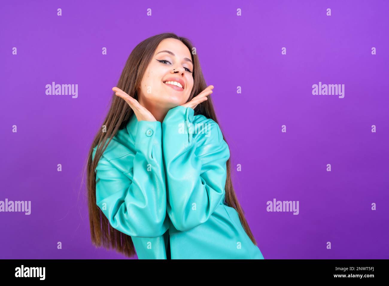Nahaufnahme einer jungen Frau, fröhlich oder lachend, isoliert auf lila Studiohintergrund in blauer Windjacke Stockfoto