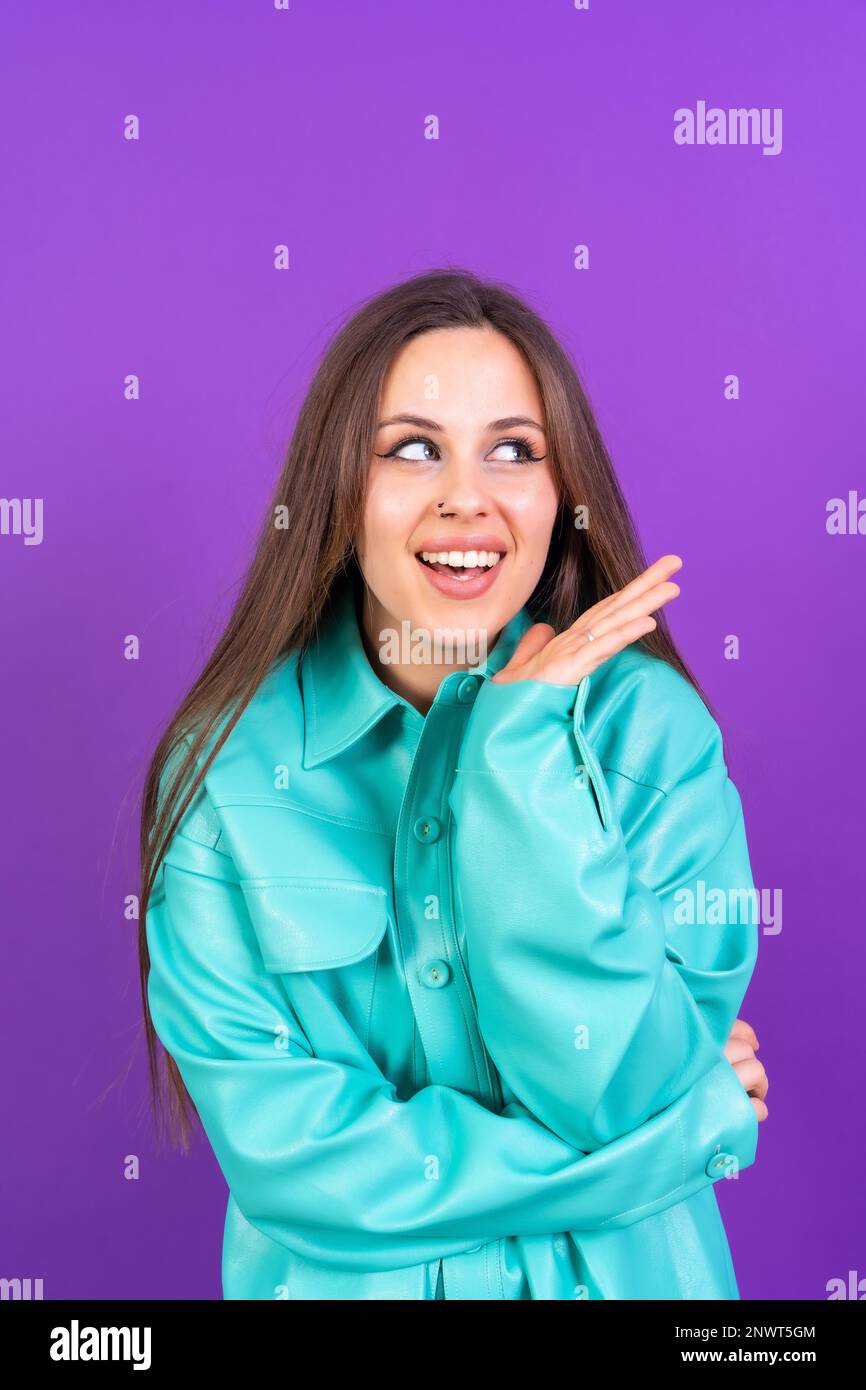 Nahaufnahme von einer jungen Frau, fröhlich isoliert auf lila Studiohintergrund in blauer Windjacke, vertikales Foto Stockfoto