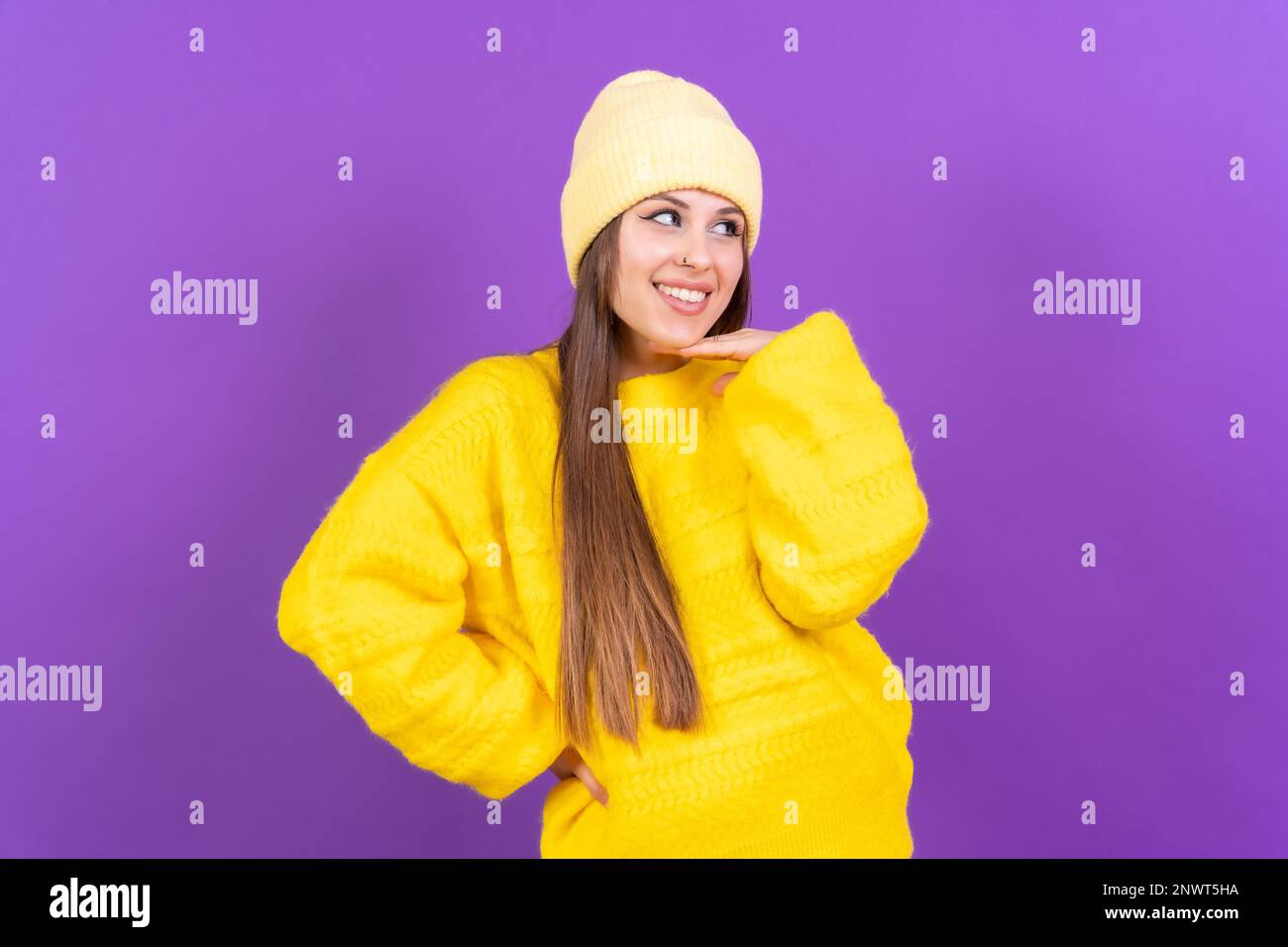 Nahaufnahme einer jungen, fröhlichen Frau, isoliert auf lila Studiohintergrund in gelbem Wollpullover Stockfoto