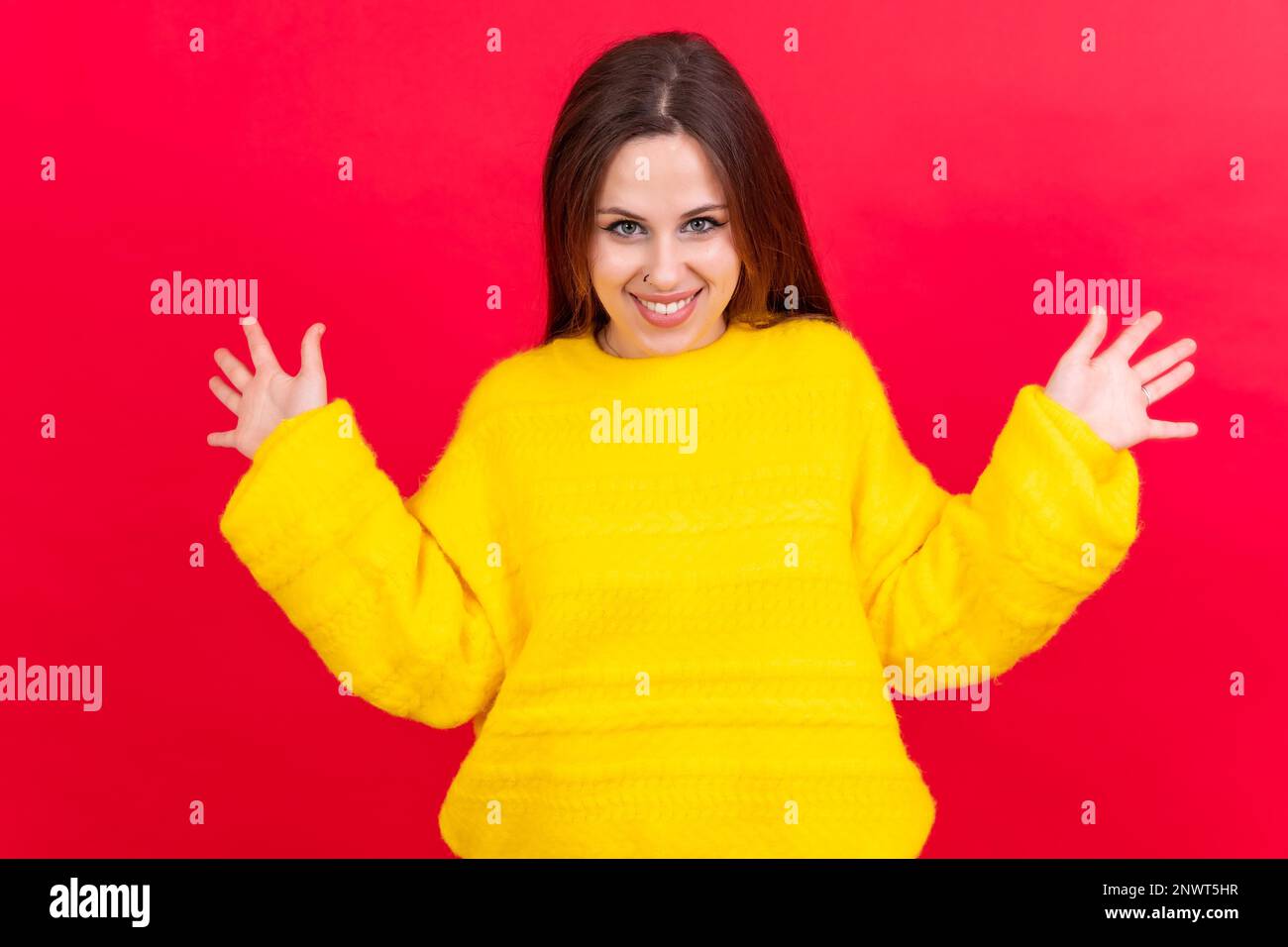 Nahaufnahme von einer jungen Frau, fröhlich isoliert auf rotem Studiohintergrund in gelbem Wollpullover Stockfoto