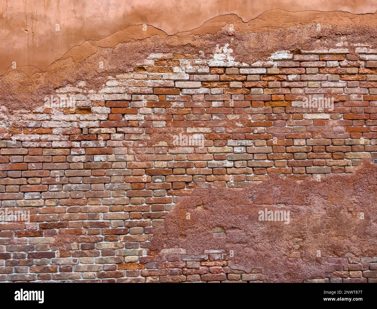 Hellbraune Malerreste an der Ziegelwand eines alten Gebäudes. Wandhintergrund im Design-Loft-Stil. Grunge rötlich-braun, mit Kopierbereich. Stockfoto