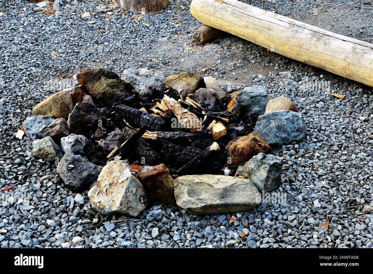 Ein Kreis aus Steinen, um ein Lagerfeuer im Freien zu umgeben, das die verbrannten Schilde des Lagerfeuers der letzten Nacht enthält. Stockfoto