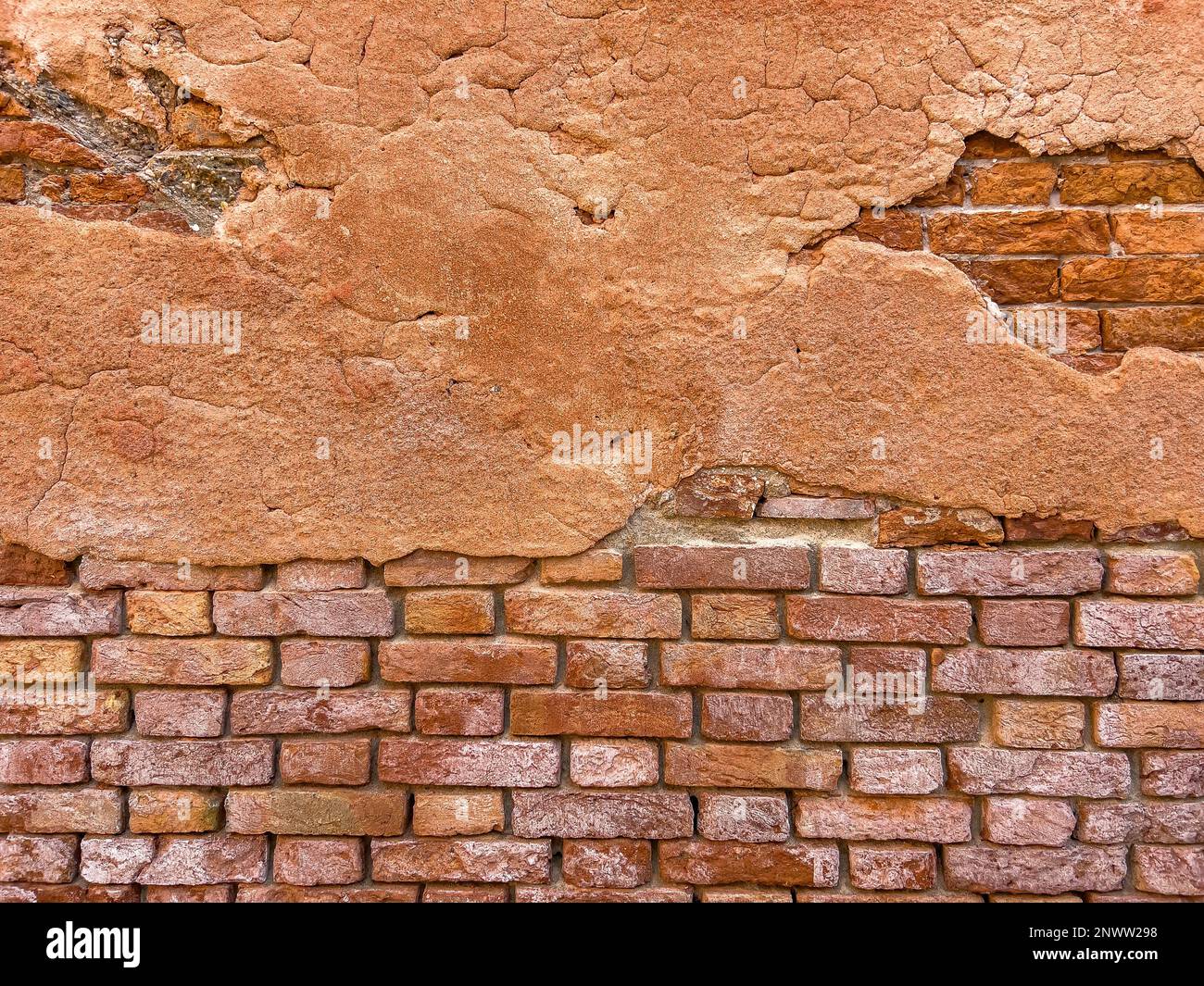 Hellbraune Malerreste an der Ziegelwand eines alten Gebäudes. Wandhintergrund im Design-Loft-Stil. Grunge rötlich-braun, mit Kopierbereich. Stockfoto