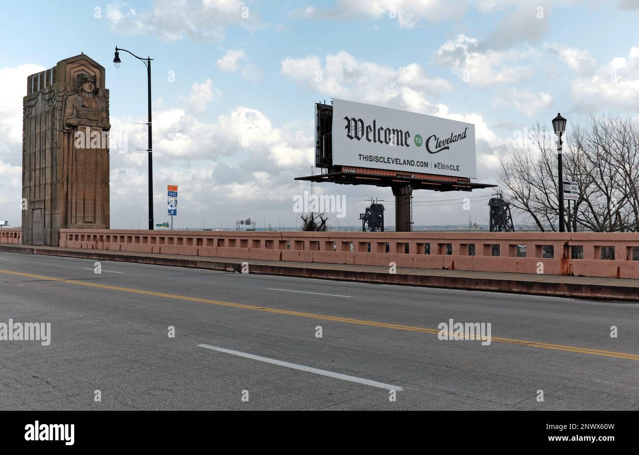Ein Schild „Willkommen in Cleveland“ in der Nähe eines Brücken-Pylons im Art-Deco-Stil des „Guardian of Traffic“ begrüßt Besucher, die die Hope Memorial Bridge in Cleveland, OH, überqueren. Stockfoto