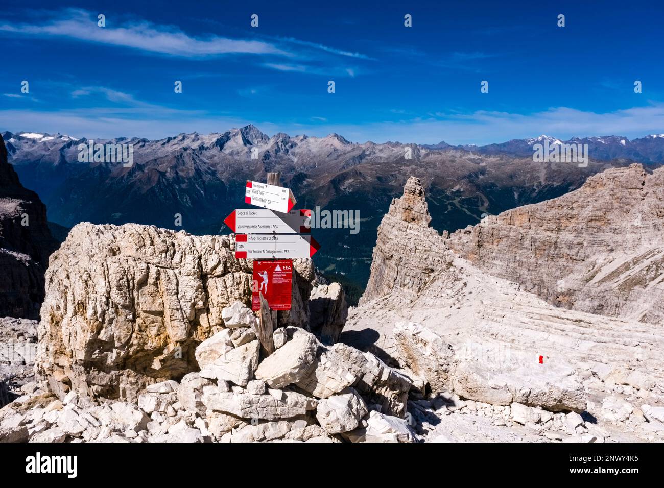 Wegweiser auf der Via ferrata Via delle Bocchette zwischen Passo del Groste und Bocca di Tucket, der Gebirgsgruppe Adamello in der Ferne. Stockfoto