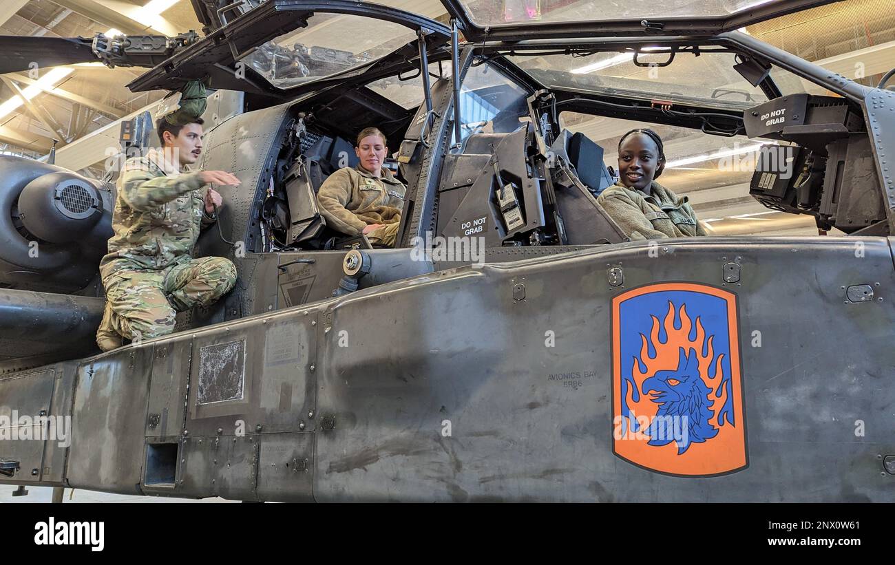 USA Militärbefehlshaber Michael Salvi, ein AH-64 D Attack Pilot der Bravo Company, 1. Bataillon, 3. Luftfahrtregiment (Angriffsbataillon), 12. Kampfluftfahrtbrigade, gibt einen Überblick über das Cockpit eines AH-64D Apache Longbow Hubschraubers an SPC. Kathleen Delage, Personalspezialist, Und 2. LT. Lasheema Rose, Personaloffizier, beide der Task Force Orion, 27. Infanterie-Brigade-Kampfteam, New Yorker Nationalgarde, zugewiesen, während einer beruflichen Fortbildungsveranstaltung in Katterbach, Deutschland, am 4. Januar 2023. Die Veranstaltung wurde für Soldaten organisiert, die der Task Force Orion zugeteilt wurden Stockfoto