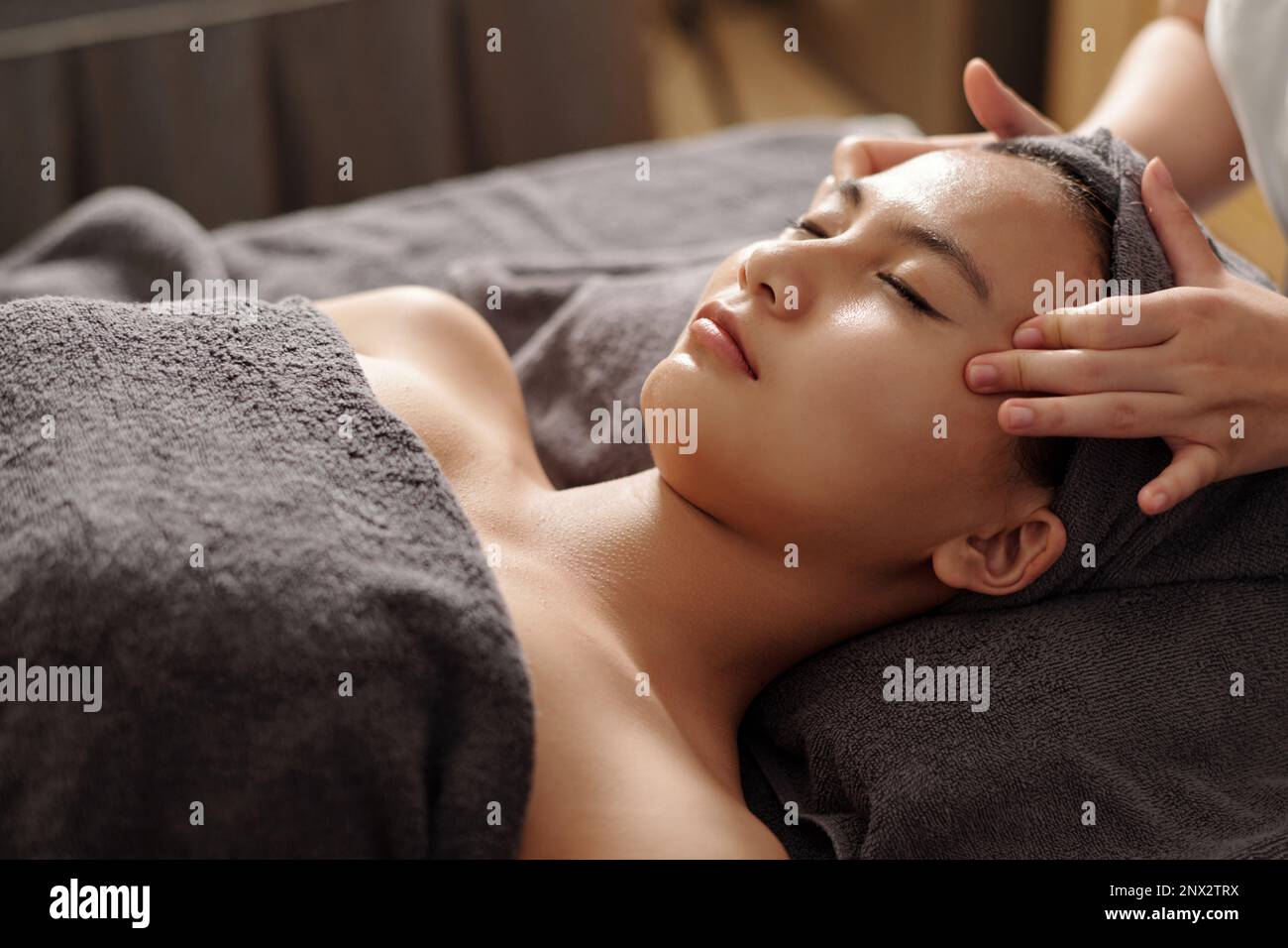 Eine junge asiatische Frau bekommt eine Gesichtsmassage im Spa-Salon Stockfoto