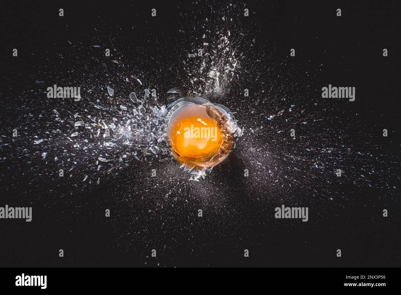 Explosion von Glaskugel und Eigelb auf schwarzem Hintergrund Stockfoto