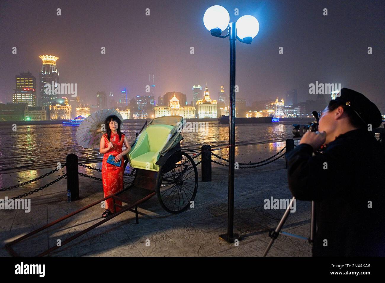 China.Shanghai: Tourist mit traditioneller Kleidung. Erinnerungsfoto. Pudong. Im Hintergrund der Bund Stockfoto