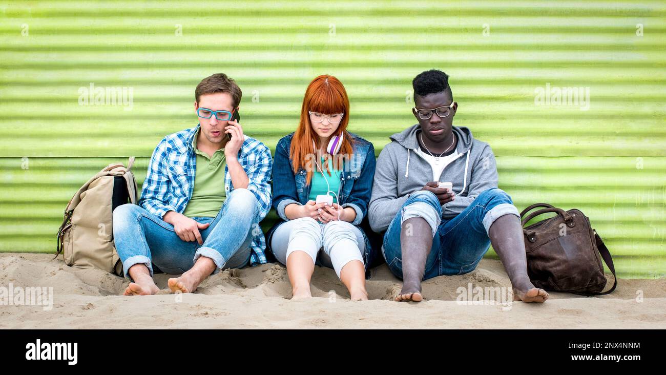 Multiethnische Freunde, die ihr Smartphone am Strand zum Entspannen benutzen - Junge gelangweilte Menschen, die von ihrem Smartphone abhängig sind - Technologiekonzept mit „Always con“ Stockfoto