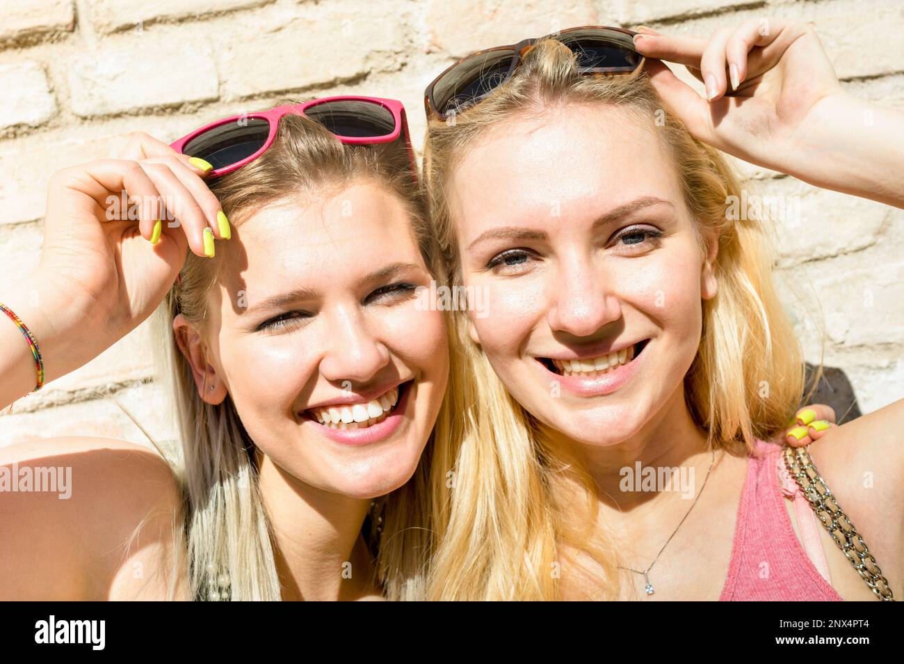 Junge Modemädchen machen Selfie gegen Steinwand - Sommerkonzept mit glücklichen Freundinnen, die Spaß miteinander haben - Beste Freundinnen mit Sonnenliege Stockfoto