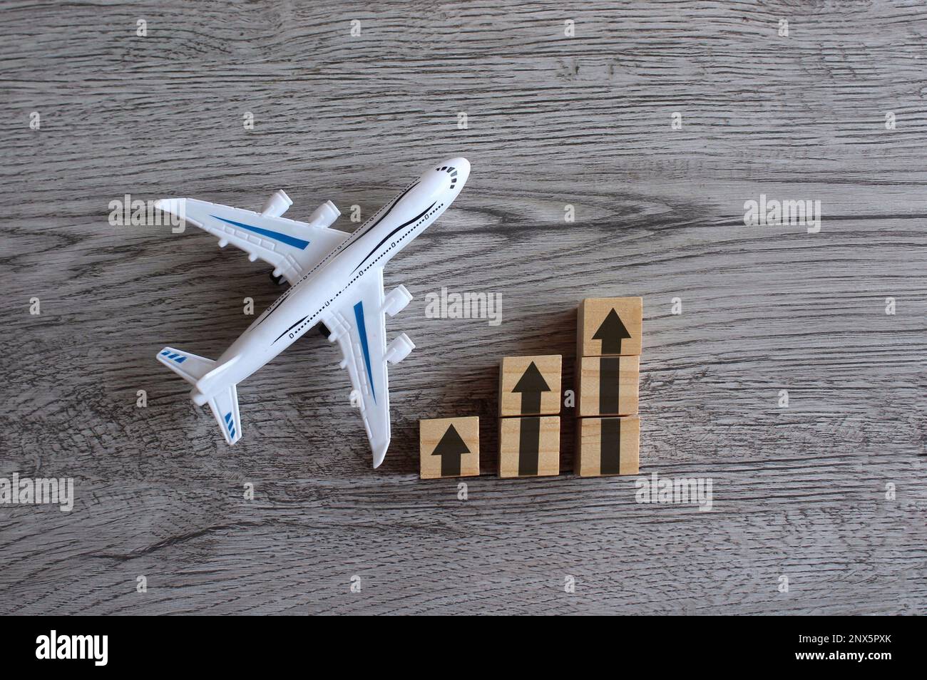 Bild von oben mit Spielzeugflugzeug und Pfeil nach oben. Die Transportbranche mit steigendem Gewinn und Wachstum, Stockfoto