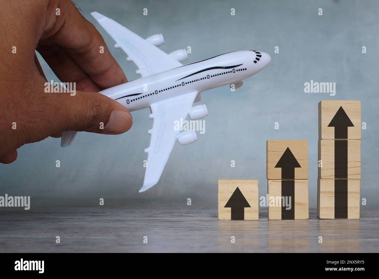 Bild von oben mit Spielzeugflugzeug und Pfeil nach oben. Die Transportbranche mit steigendem Gewinn und Wachstum, Stockfoto