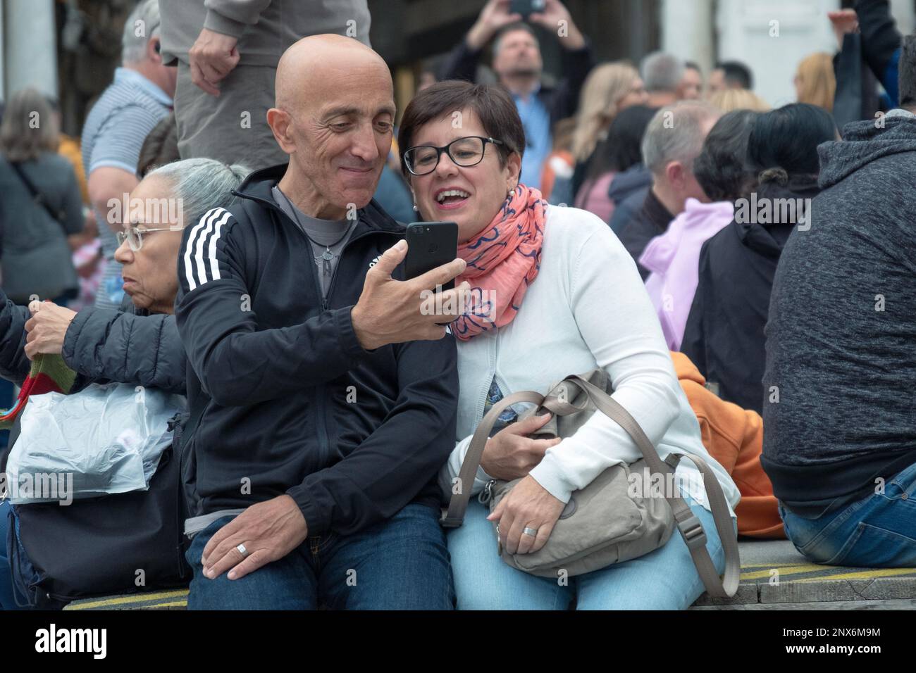 Ein Paar mittleren Alters schaut sich seine Selfie-Fotos auf der Piazza San Marco in Venedig an Stockfoto