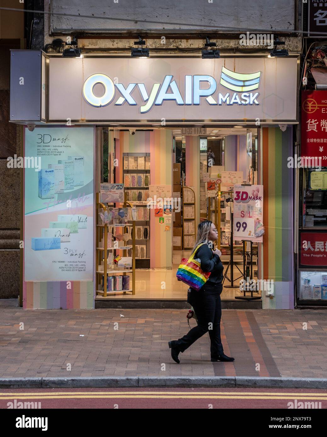 Hongkong, Hongkong. 01. März 2023. Eine maskenlose Frau läuft vor einem Spezialmaskenladen in Causeway Bay, Hongkong. Mit schätzungsweise 300 Fachmaskenläden in ganz Hongkong, wird die plötzliche Entfernung des Maskenmandats am 1. März 2023 durch die Regierung voraussichtlich Tausende Quadratmeter Verkaufsfläche freisetzen. Das verheißt nichts Gutes für die Wirtschaft Hongkongs, da die Anzahl der Einzelhandelsleasingverträge in den letzten Jahren zurückgegangen ist, obwohl die Rückkehr von Touristen nach Hongkong neue wirtschaftliche Chancen schaffen könnte. Kredit: SOPA Images Limited/Alamy Live News Stockfoto