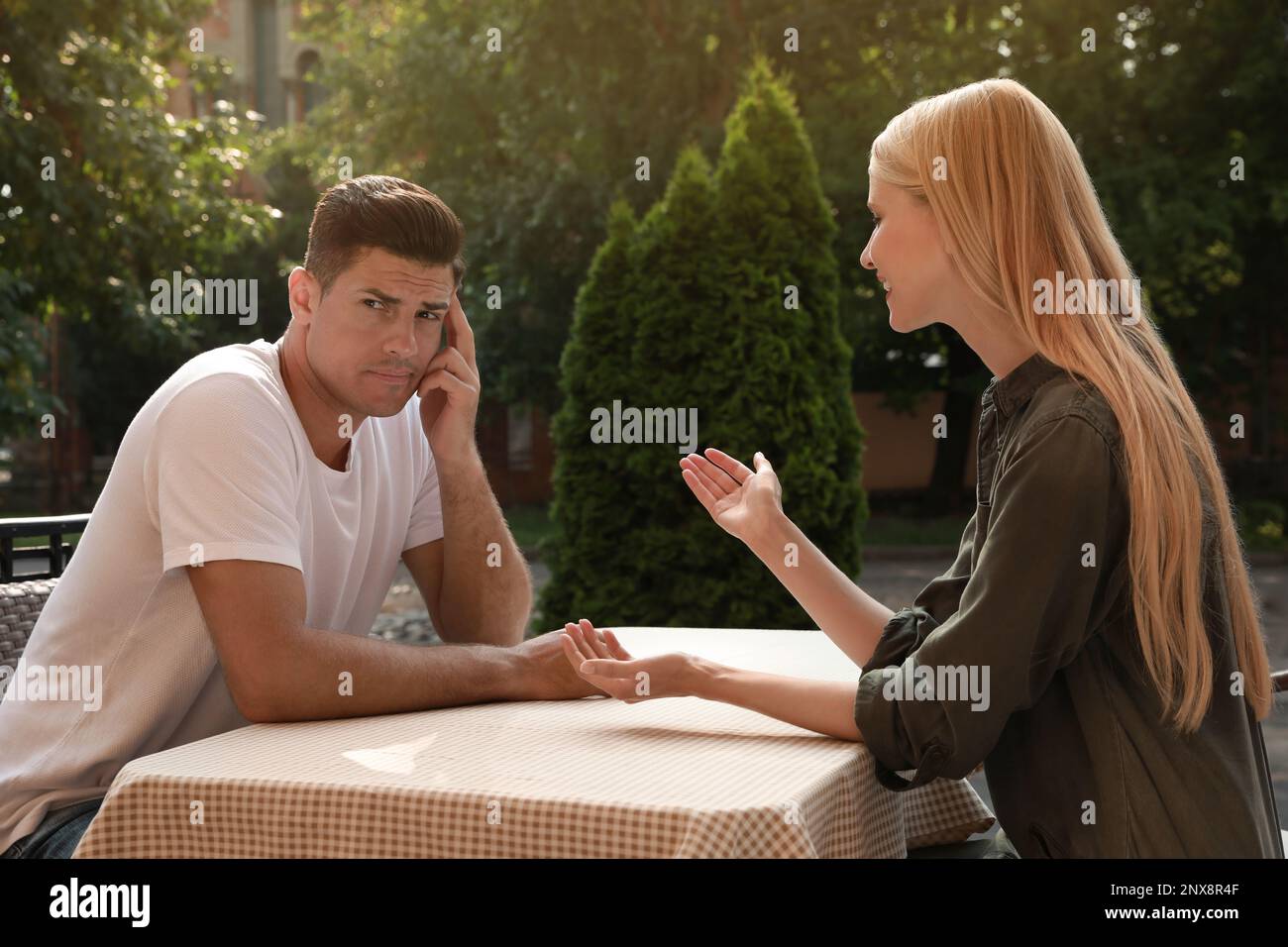 Ein Mann hat ein langweiliges Date mit einer gesprächigen Frau im Café draußen Stockfoto