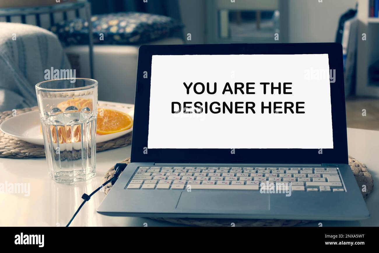 In einer modernen Inneneinrichtung steht ein Laptop auf dem Tisch. Text auf Laptop-Bildschirm Sie sind hier der Designer Stockfoto