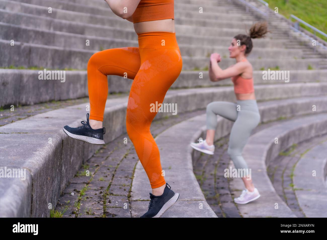 Zwei junge, weiße Sportlerinnen in Sportkleidung führen auf einer Treppe ein Trainingsprogramm durch Stockfoto