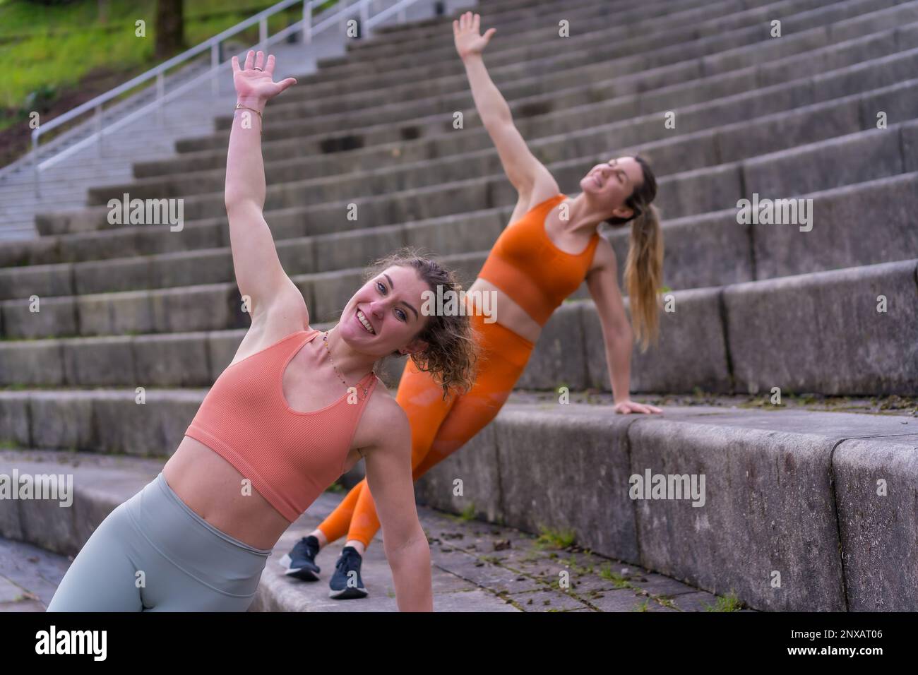 Zwei junge, weiße Sportlerinnen in Sportkleidung führen auf einer Treppe ein Trainingsprogramm durch Stockfoto