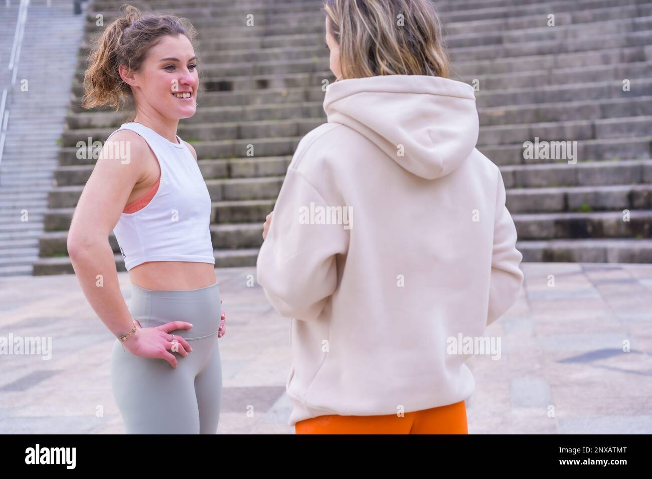 Zwei junge weiße Frauen, die sich unterhalten, während sie in einem Park stehen Stockfoto