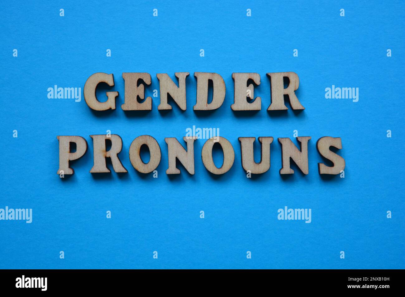 Geschlechterpronomen, Wörter in hölzernen Buchstaben isoliert auf blauem Hintergrund Stockfoto