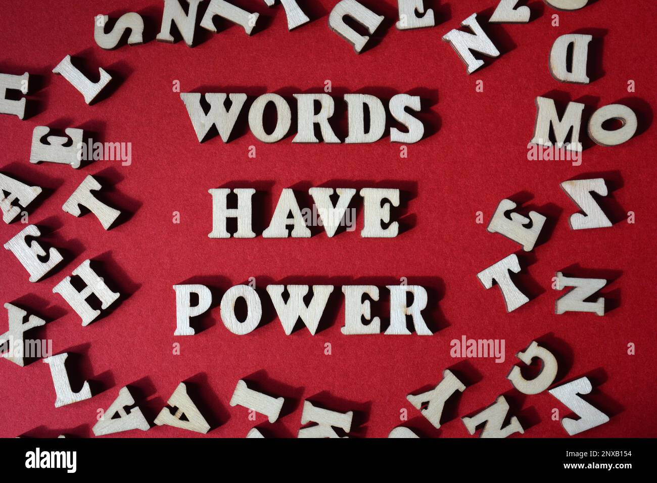 Wörter haben Macht, Ausdruck umgeben von zufälligen hölzernen Buchstaben isoliert auf rotem Hintergrund Stockfoto