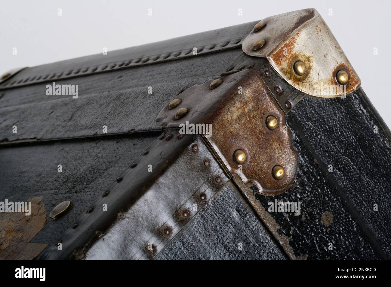 Nahaufnahmen eines altmodischen Holzkoffers. Ein schwarzer Kofferraum mit metallverstärkten Ecken und mit Leder verzierten Kanten. Hintergrundbild. Stockfoto