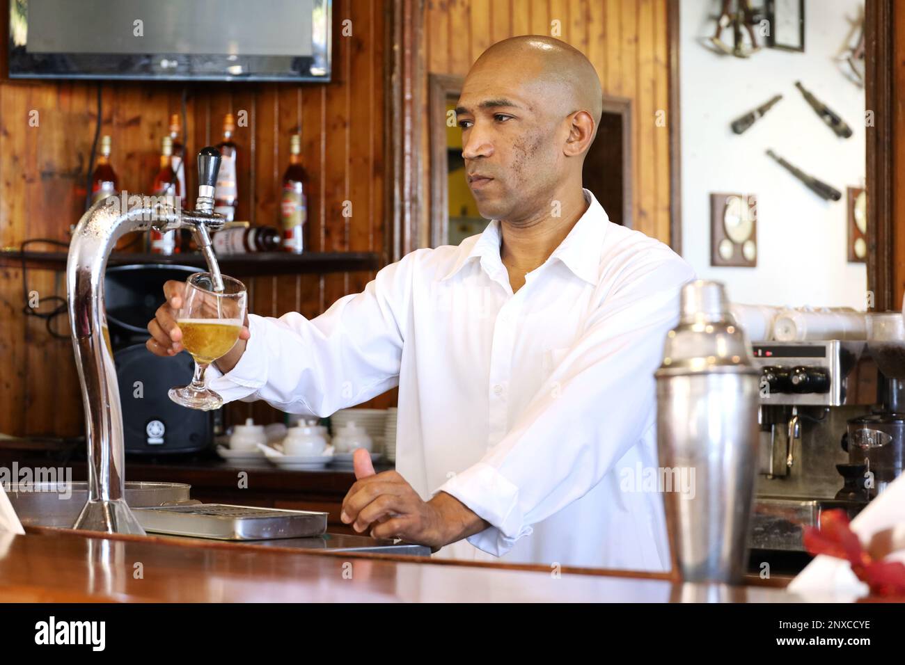 Schwarzer Barkeeper gießt Bier an der Bar des Touristenresorts ein Stockfoto