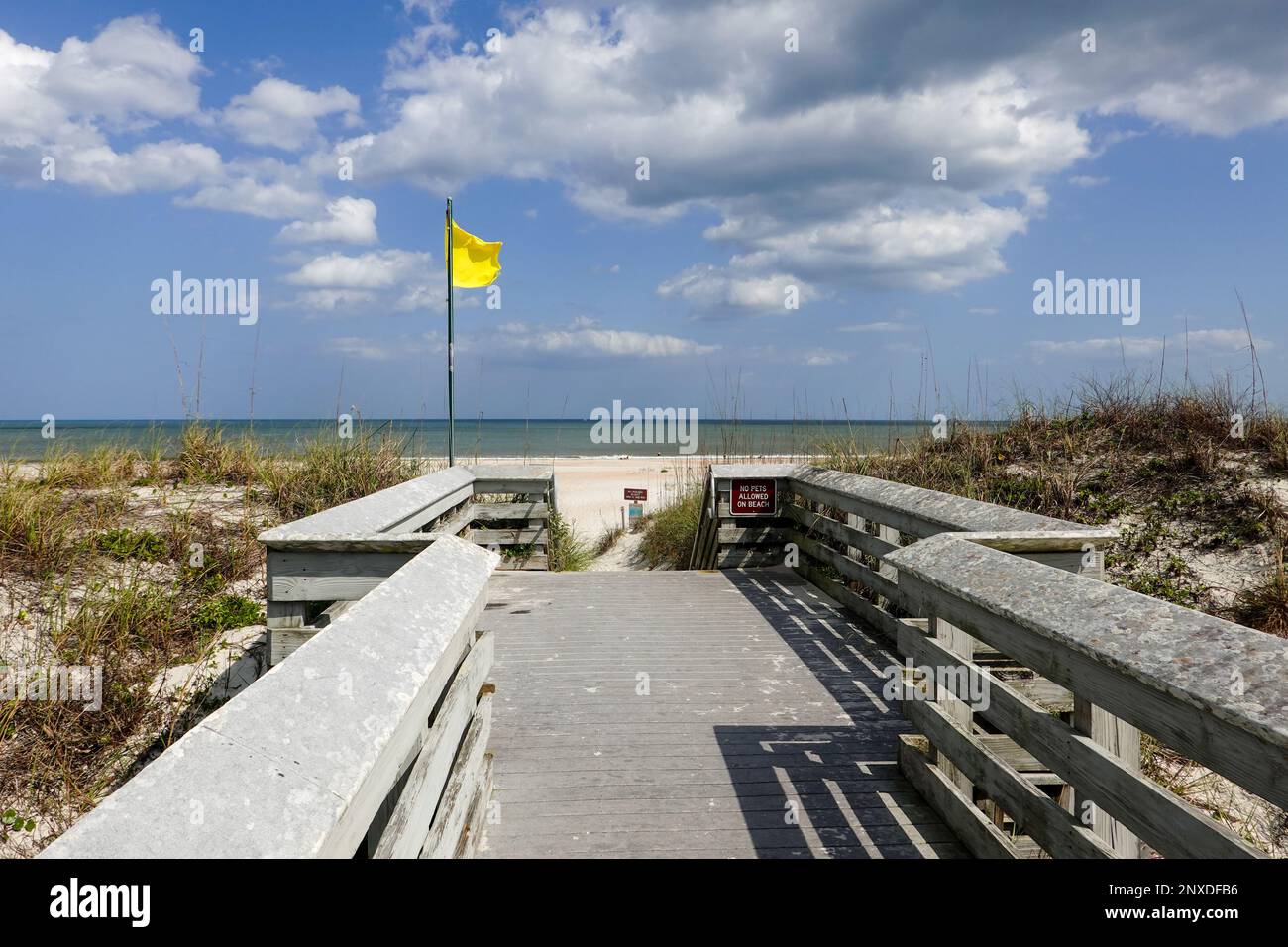 Gelbe Flagge, die auf der Promenade zum Strand, Anastasia State Park, St. Augustine Beach, Florida, USA. Stockfoto