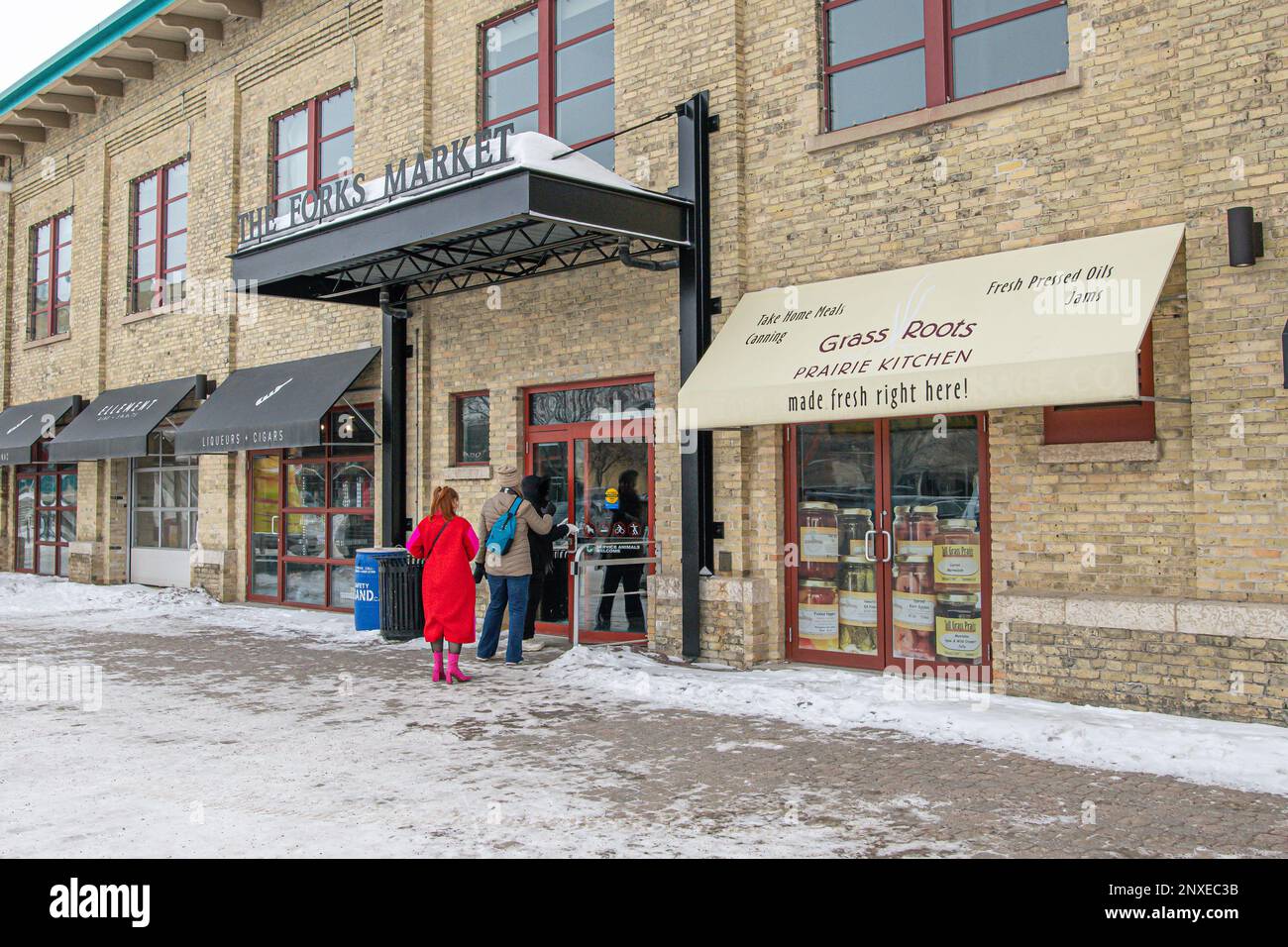 Drei Personen gehen im Winter in den Eingang zum Forks Market in Winnipeg, Manitoba, Kanada. Stockfoto