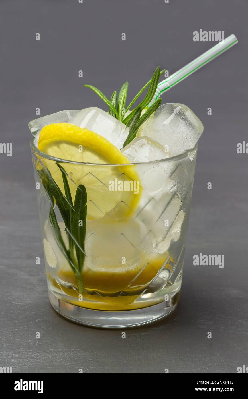 Sommergetränk mit Zitrone und Eis, Strohhalm in einem Glas. Draufsicht. Grauer Hintergrund. Stockfoto